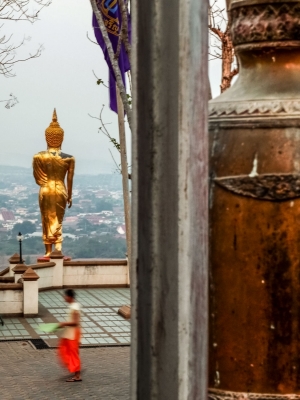 Monk-walking-past-Golden-Budha-statue-Luang-Prabang-Laos
