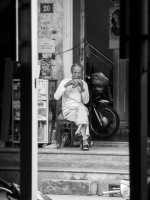 Old-man-eating-in doorway-Hue-Vietnam