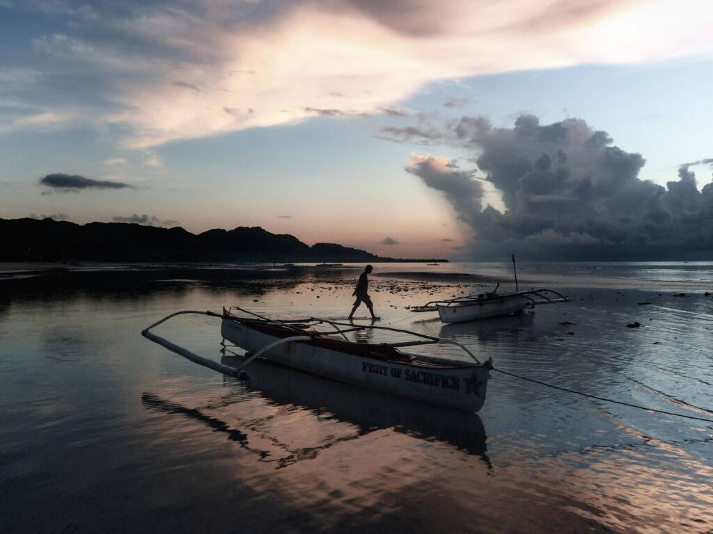 Fisherman and bangkas at sunrise Anda beach Bohol Philippines